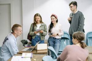 a group of students talking to each other in a classroom.