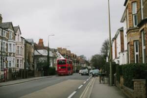  A street with cars and a double-decker bus with homes on each side.